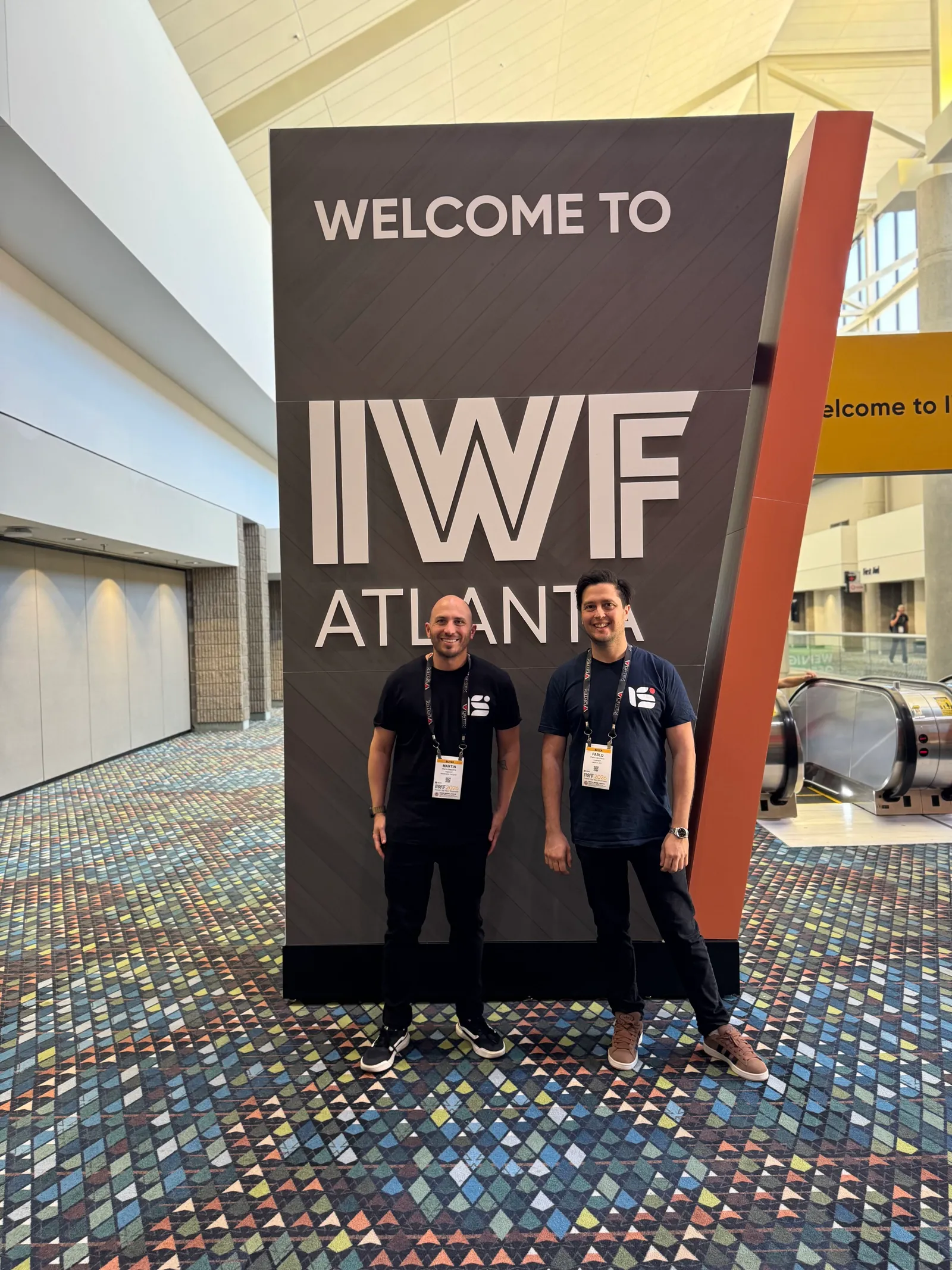 Lagarsoft co-founders Martin Daguerre and Pablo Gancharov standing in front of the large “Welcome to IWF Atlanta” sign at the entrance to the show.
