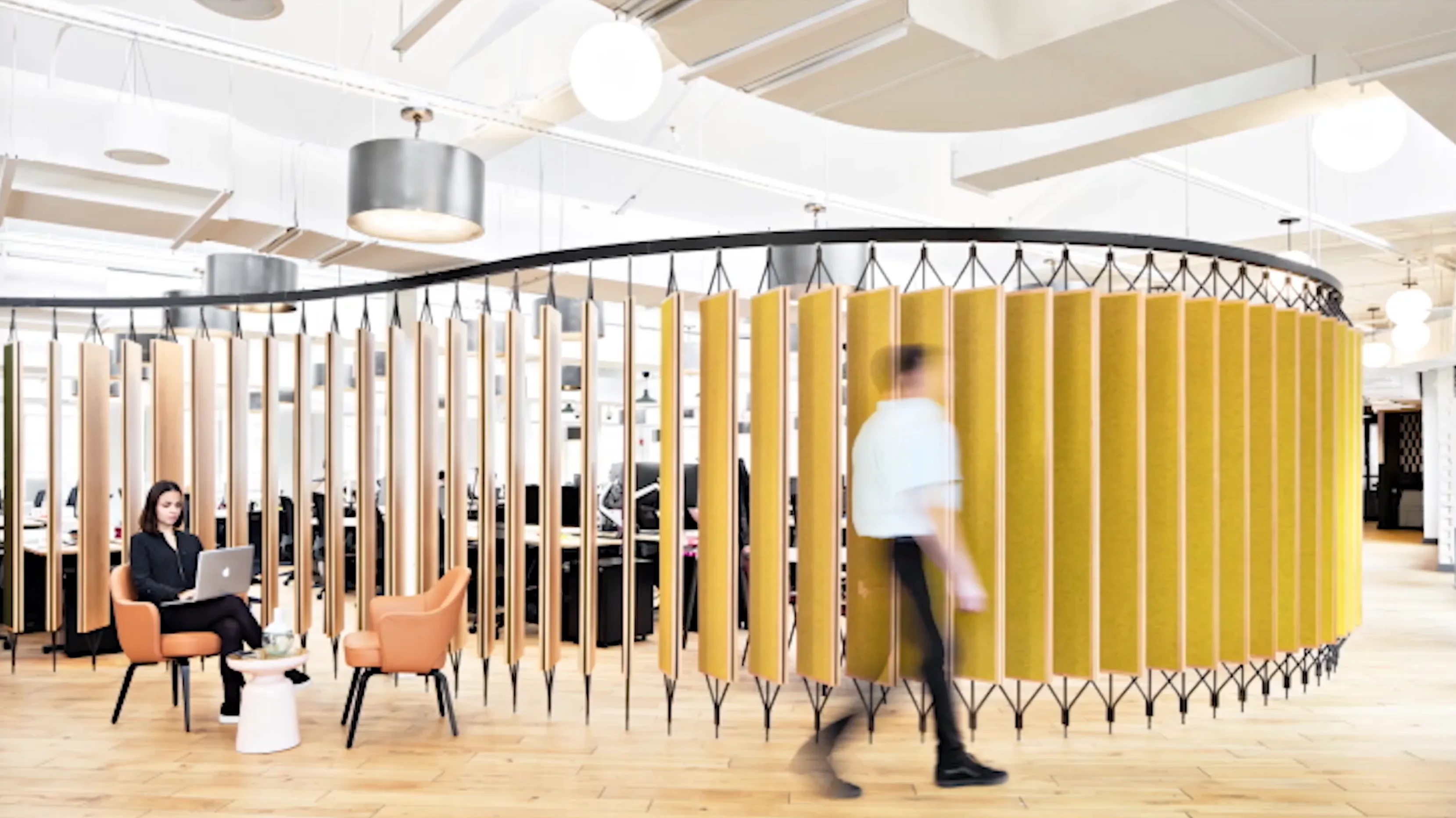 Person walking through a modern coworking space with a curved yellow partition