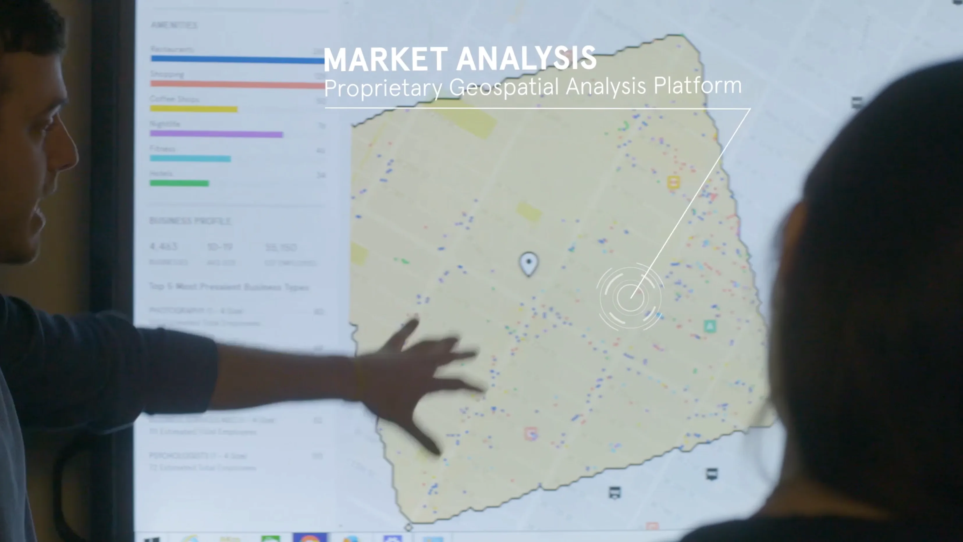 Two analysts reviewing a proprietary geospatial market analysis dashboard on a large screen