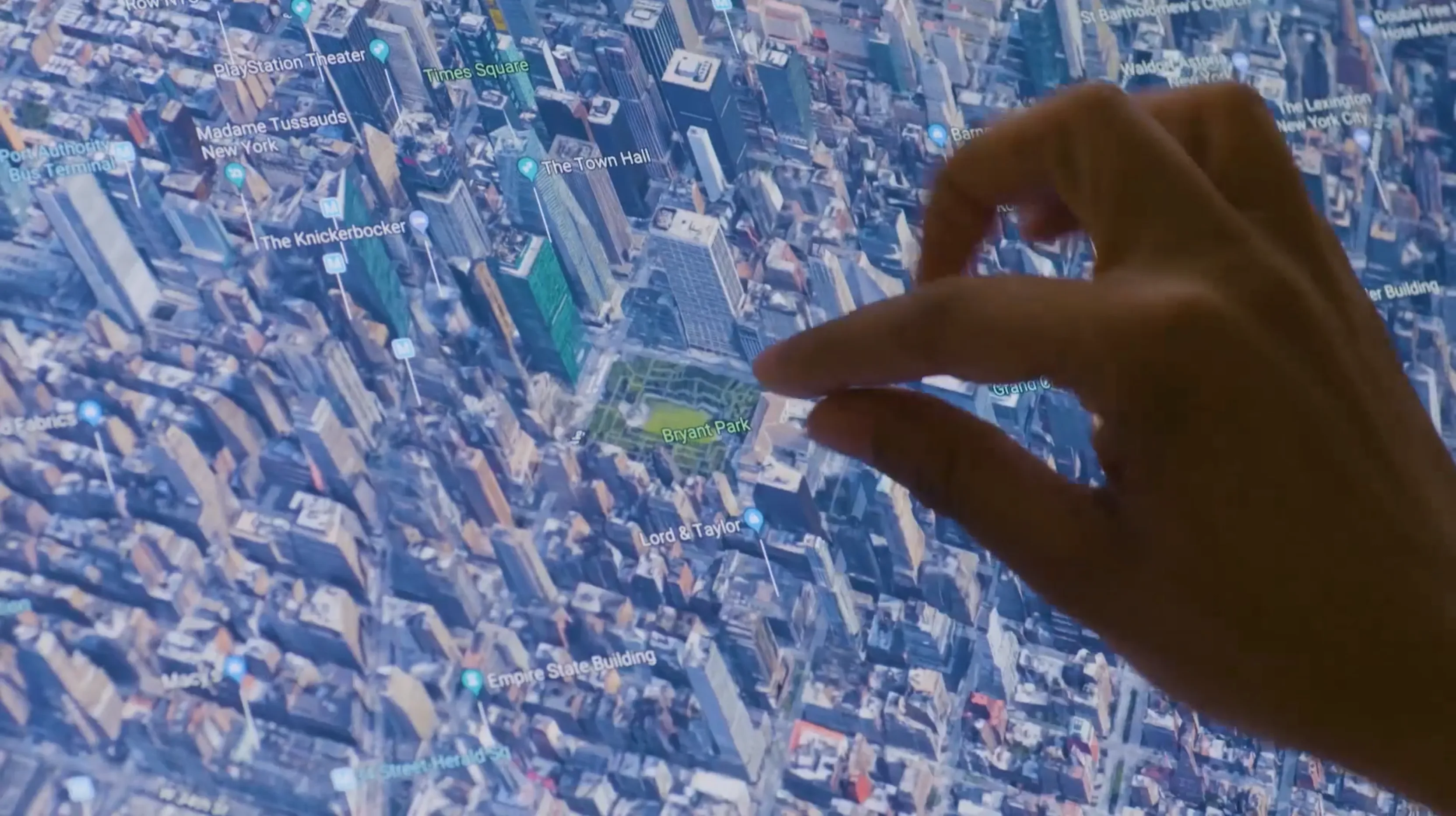 Hand pointing at a specific building on a zoomed-in Manhattan property map
