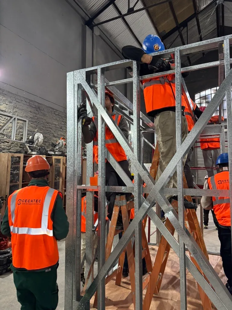 Course participants on ladders screw together a light gauge steel wall frame during the CECATEC steel framing installer course.