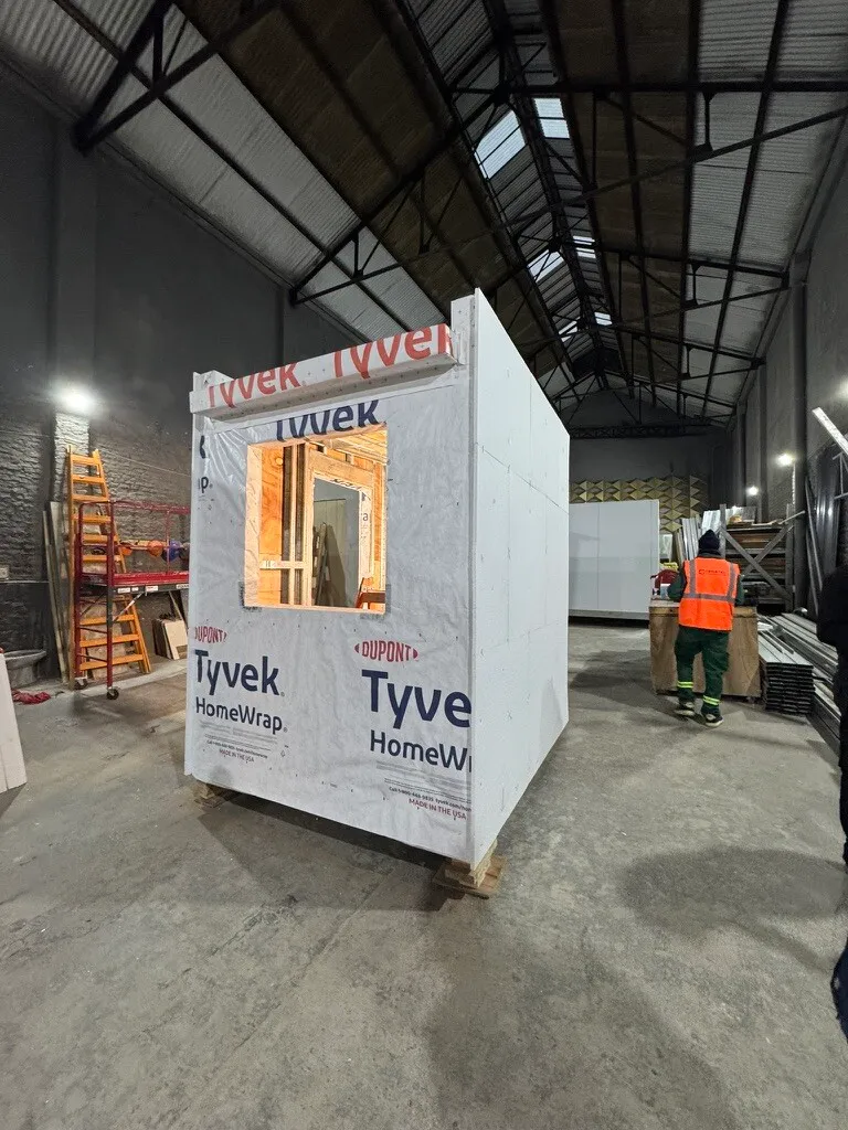 A finished steel framed module wrapped in DuPont Tyvek HomeWrap with a window opening, built during the course.